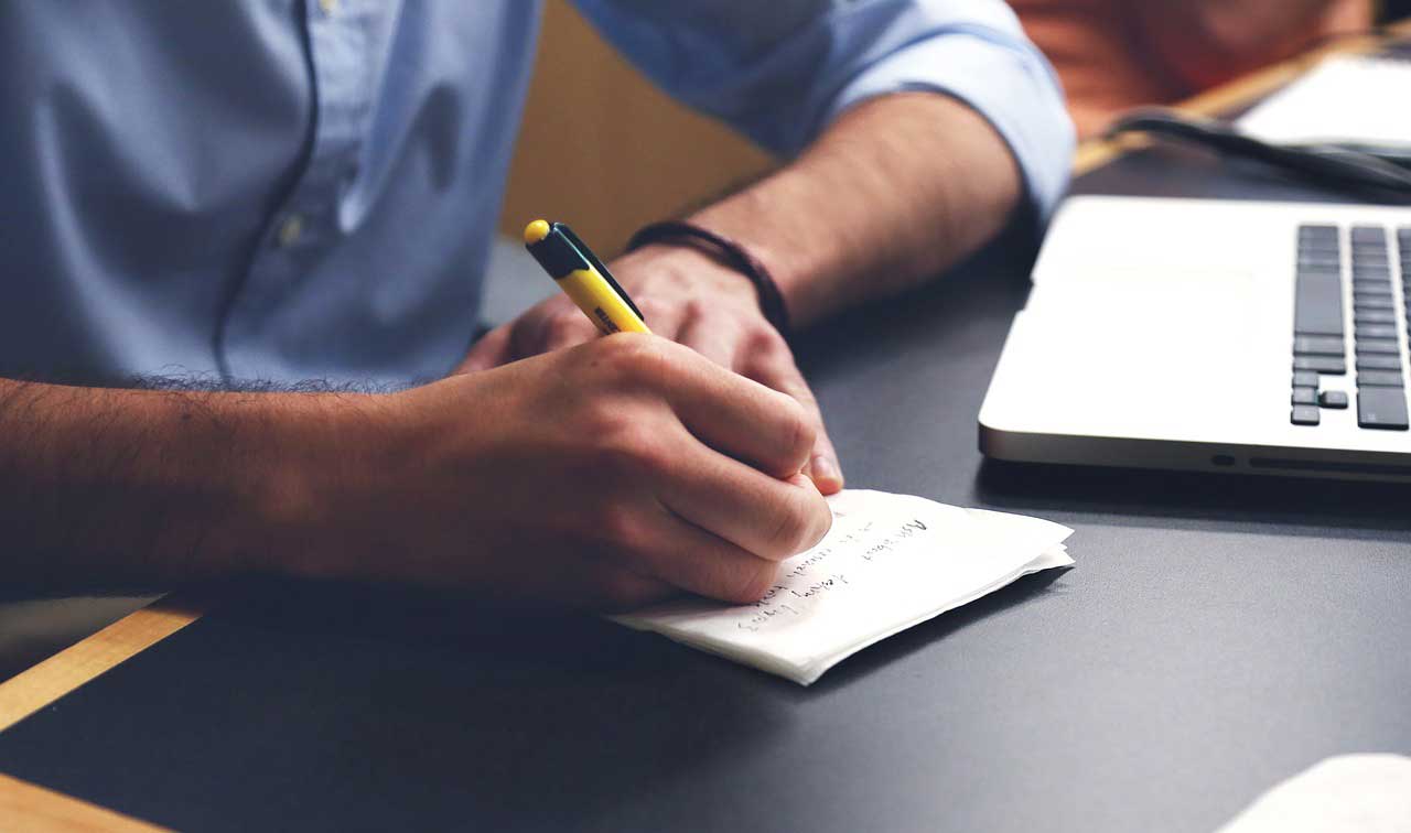 Man writing notes at a desk while learning the advantages of digital checks.