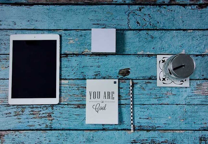 A blue wooden table with an iPad and other items on it.