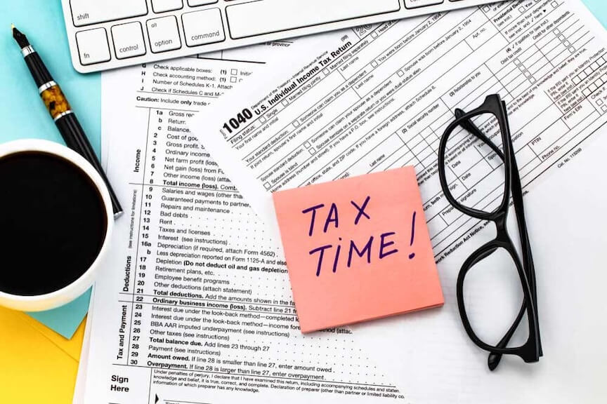 A picture of a checklist with a pen, surrounded by various tax documents