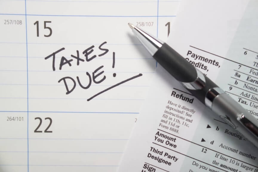 A graphic showing a worried person surrounded by tax documents and red penalty" stamps"
