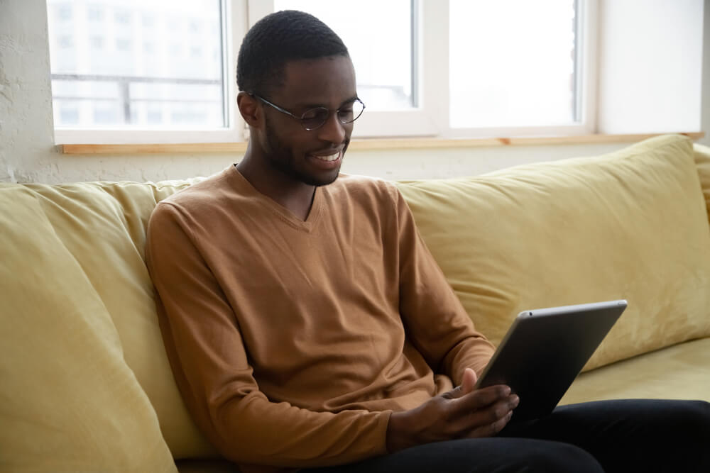 Smiling African American Man Holding and Using Tablet