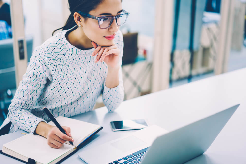 Pensive Female Administrative Assistant Checking Report on Laptop Reading Information