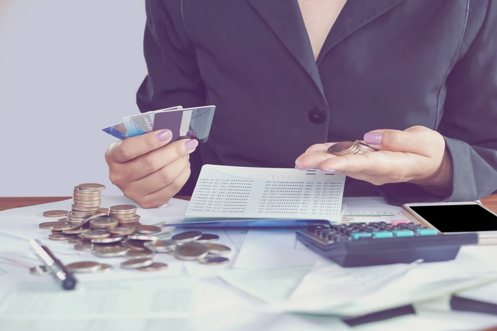 Business Woman Hand Calculating Her Monthly Expenses During Tax Season With Coins