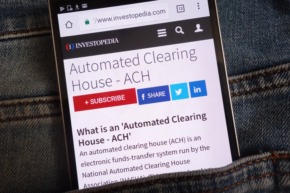 An Article About Automated Clearing House (ACH) On Investopedia Website Displayed on Smartphone Hidden in Jeans Pocket