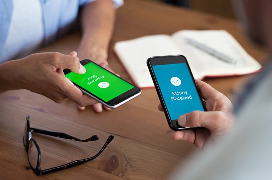 Two people on their iPhones making a transactions.