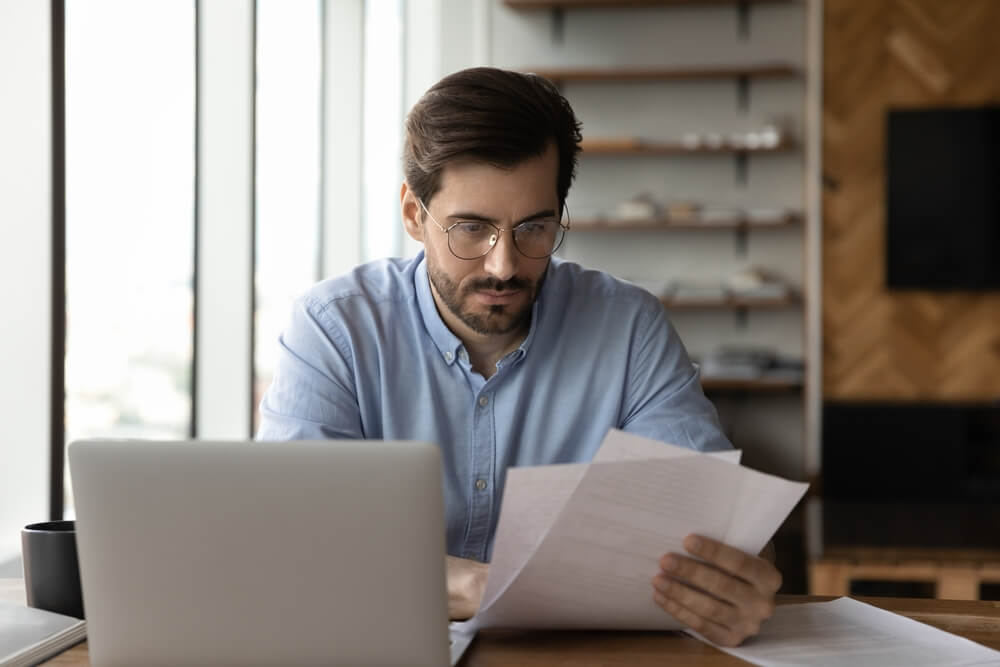 Focused Businessman Reviewing Paper Reports Received Letter Notice From Bank Working At Office