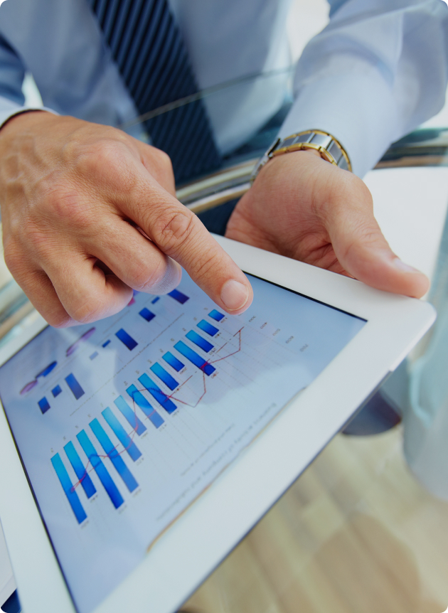 Businessperson taps a tablet displaying blue bar charts and a line graph.